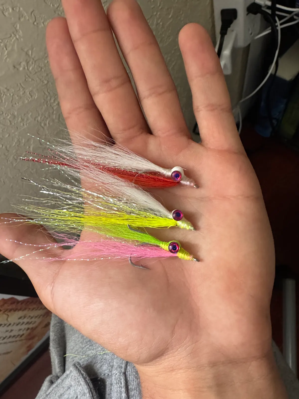 Three hand-tied flies with flashy tails laid out in an open palm